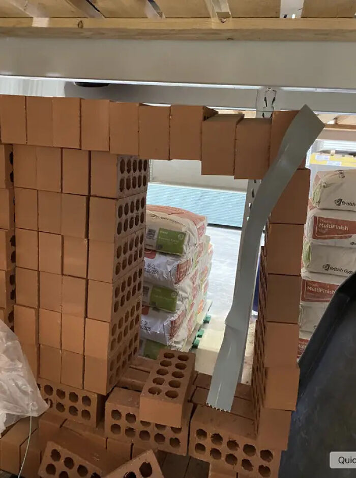 A partially collapsed stack of bricks in a warehouse, depicting disarray caused by service industry workers.