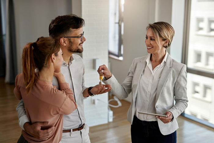 A realtor handing keys to a happy couple, symbolizing the inheritance being used to help his sis. A realtor handing keys to a happy couple, symbolizing the inheritance being used to help his sis.