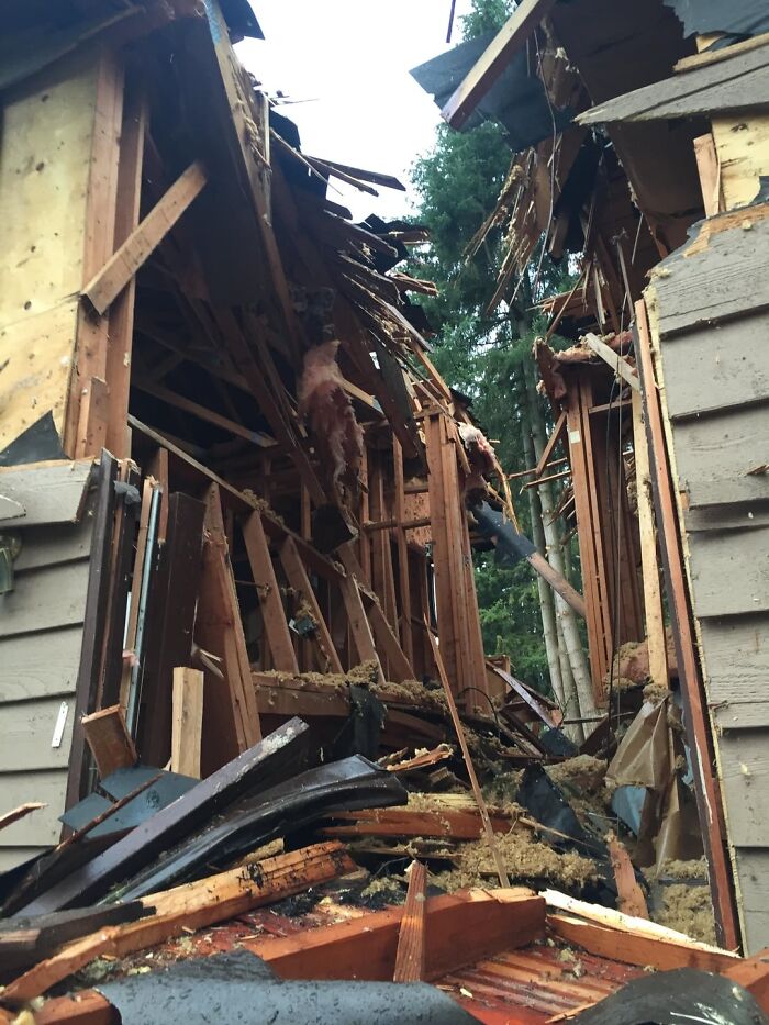A severely damaged house with a collapsed roof and exposed interior, depicting a terrifying 'we need to leave now' event.