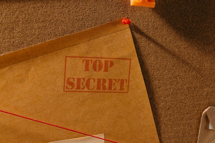 Top secret manila envelope with red string, related to cults and internet rabbit holes.