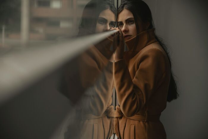 A woman looking out a window, reflecting on internet rabbit holes and the disturbing nature of cults.