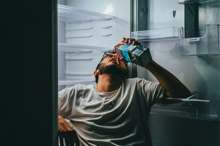 A person drinking directly from a carton inside a fridge, depicting the disturbing aspects of internet rabbit holes and cults.