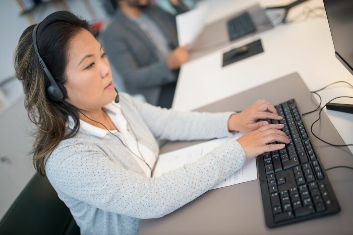Woman with headset typing on a keyboard, representing research into internet rabbit holes and cults.