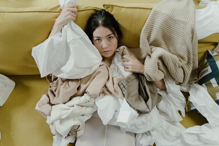 Woman buried under laundry, illustrating the feeling of being disturbed by cults and internet rabbit holes.