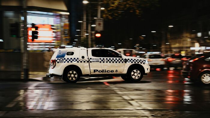 A police vehicle speeding through a city at night, representing urgent 'we need to leave now' moments.