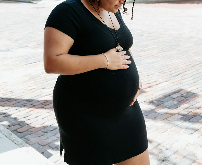 A pregnant woman in a black dress, illustrating infuriating MILs stories.