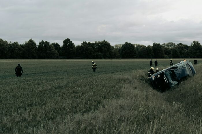 First responders at an overturned car accident in a field, showing a scarily accurate intuition of danger.
