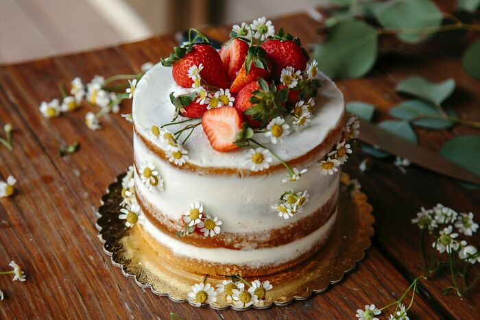 A beautiful cake decorated with strawberries and small flowers, representing celebration and guest experiences.