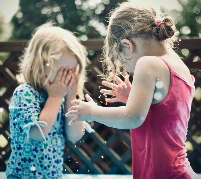 Children playing outside, one looking distressed. This image could represent a moment related to a mother's discipline. Children playing outside, one looking distressed. This image could represent a moment related to a mother's discipline.