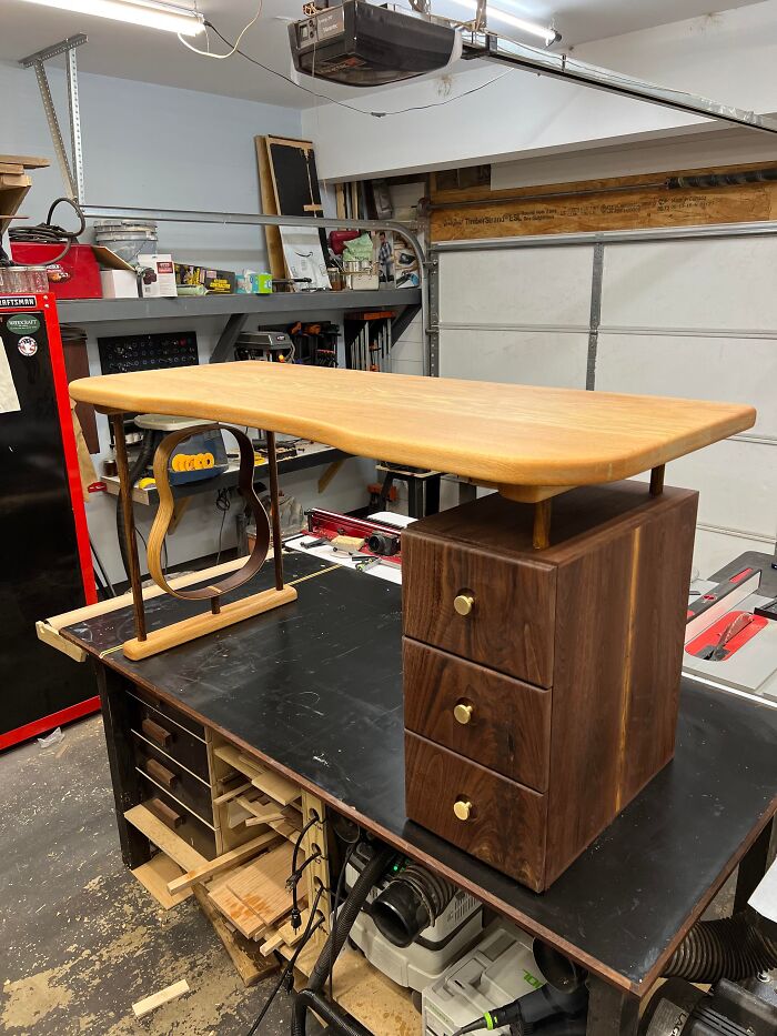 A creative home DIY project: a custom-made wooden desk with a guitar-shaped leg and three drawers.