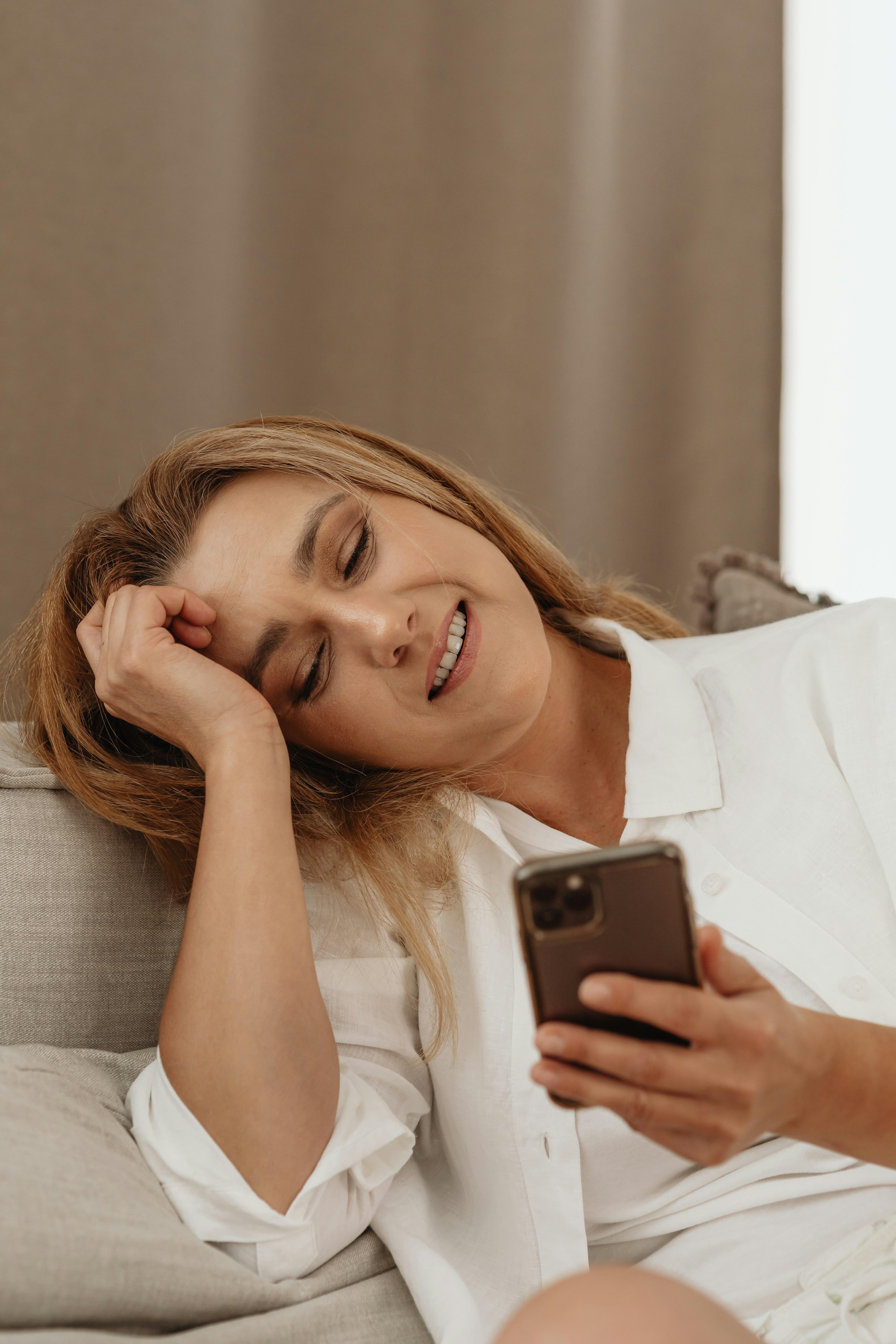 A woman smiling while looking at her phone, reflecting a suspicious situation a guy discovers on wife's phone.