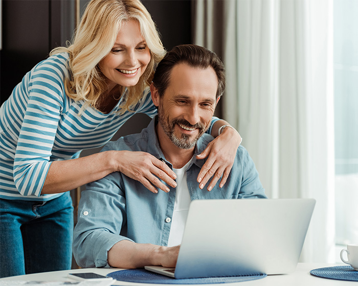 Happy couple using a laptop, representing healthy relationships and libido discussion.