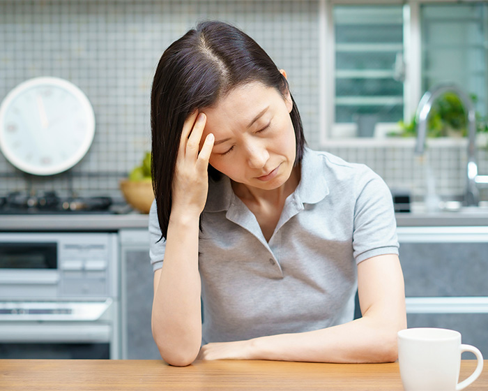 Woman experiencing low libido, holding her head in a kitchen, sparking debate on women's health.