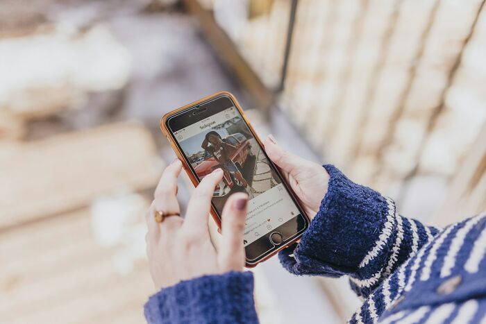 Hands holding a phone, viewing Instagram, depicting how modern experiences can align with peoples intuition.
