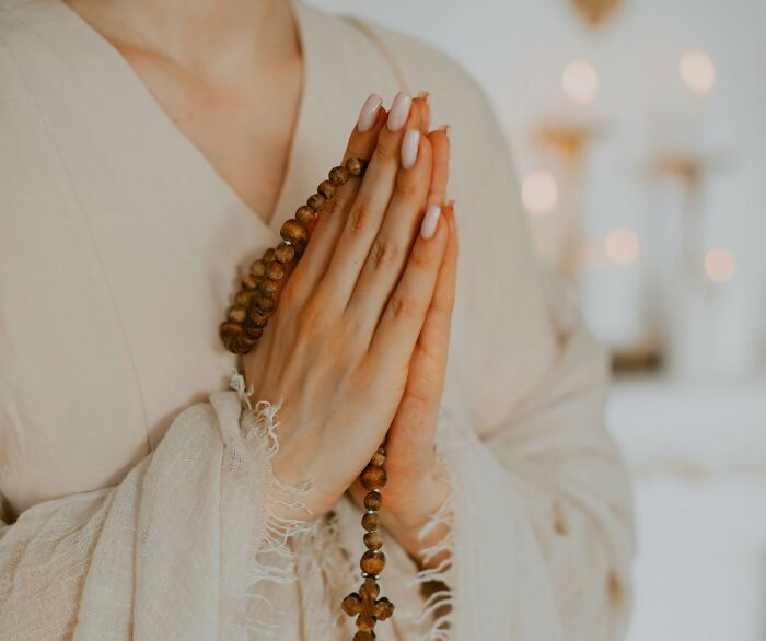 Woman in prayer with rosary beads, contemplating unhinged therapist moments and personal recovery.
