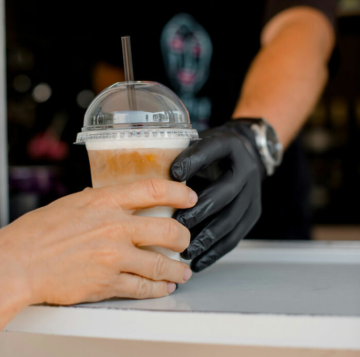 A barista handing a cold drink to a customer, a simple exchange that could precede or follow instant justice.