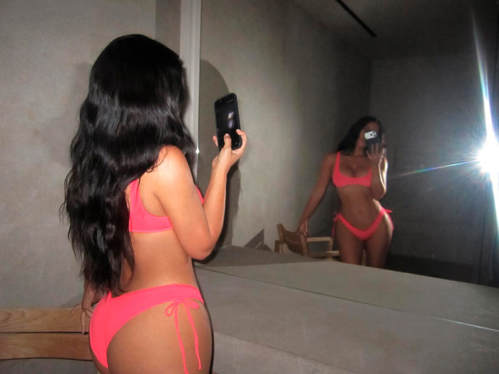 Kim Kardashian taking a mirror selfie, showing off her brand's new micro bikini. Kim Kardashian taking a mirror selfie, showing off her brand's new micro bikini.