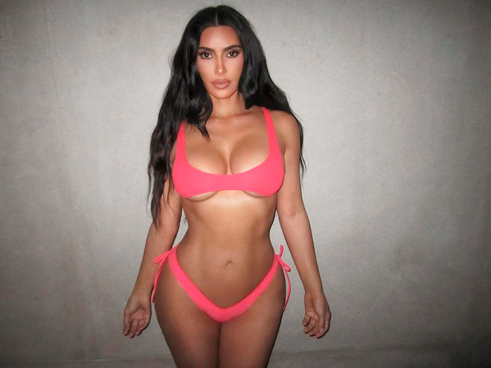 Kim Kardashian posing in a pink micro bikini, promoting her brand's new swimwear collection. Kim Kardashian posing in a pink micro bikini, promoting her brand's new swimwear collection.