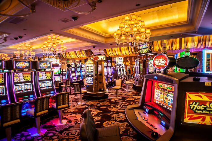 A vibrant casino floor with numerous slot machines and glowing chandeliers, suggesting a moment of instant justice.