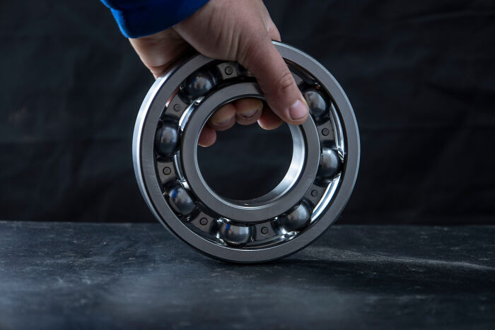 A hand holding a ball bearing, an example from the manufacturing industries that actually make millions.