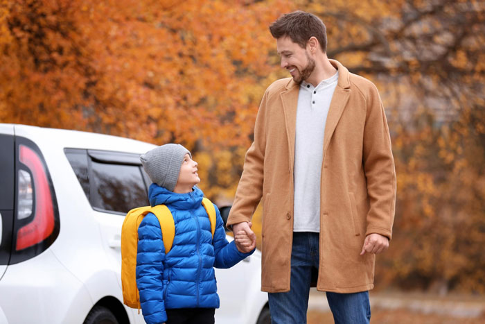 Man holds hands with a young boy with a yellow backpack, symbolizing a father with his baby. Man holds hands with a young boy with a yellow backpack, symbolizing a father with his baby.