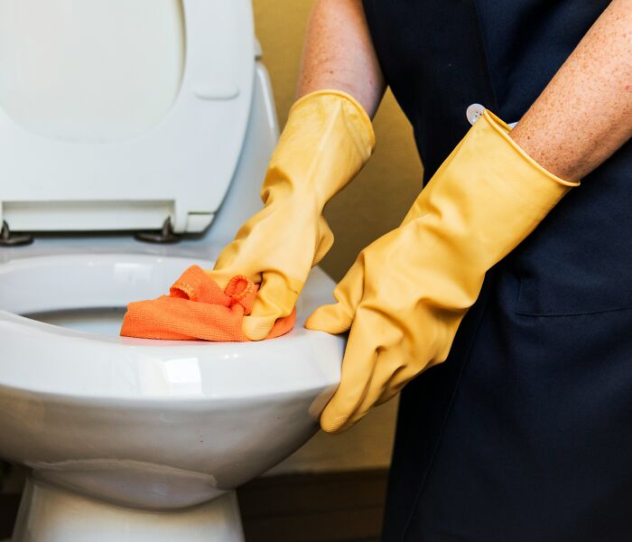 A person in yellow gloves cleaning a toilet, illustrating the realities of being married.