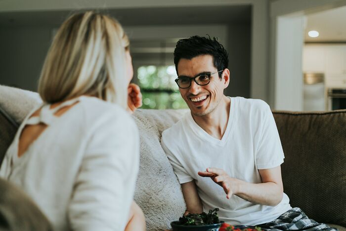A happy couple smiling and talking on a couch, representing realities of being married.