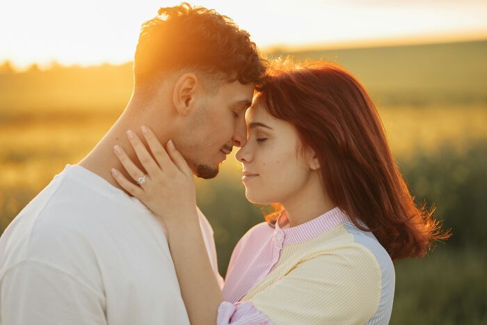 A couple with heads touching in a field at sunset, symbolizing the beautiful realities of being married.