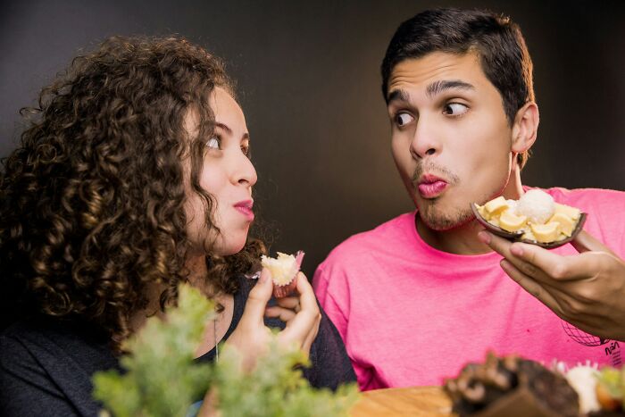 A married couple eating dessert, with the man making a funny face, highlighting the realities of being married.