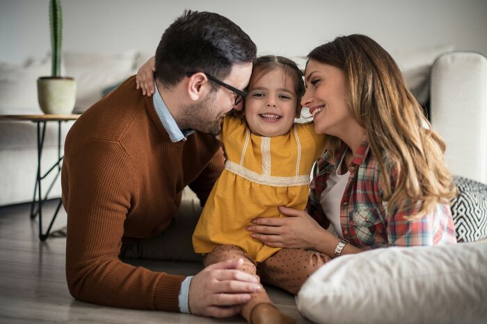 A joyful family with a young girl smiling between her parents, reflecting the realities of being married.