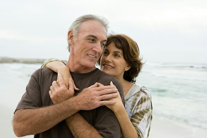 A happy, older couple embracing on a beach, showing the realities of being married.