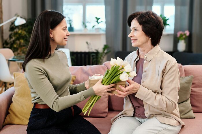 A young woman giving flowers and a gift to an older woman, sharing the realities of being married.