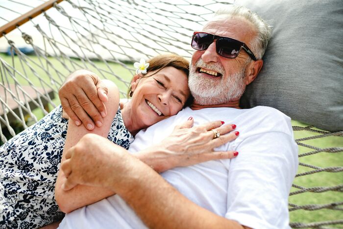 A smiling elderly couple relaxing in a hammock, showcasing the peaceful realities of being married.