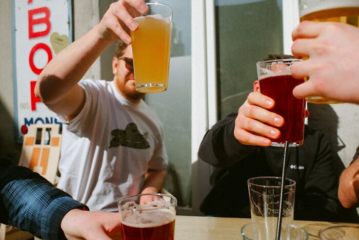 Friends toasting with beers, illustrating social culture shocks with international partners.