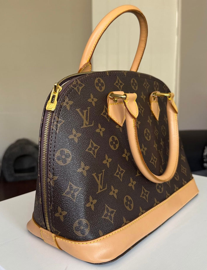 A close-up of a brown Louis Vuitton designer bag with its distinct monogram pattern and light tan leather accents. The bag might be a fake. A close-up of a brown Louis Vuitton designer bag with its distinct monogram pattern and light tan leather accents. The bag might be a fake.