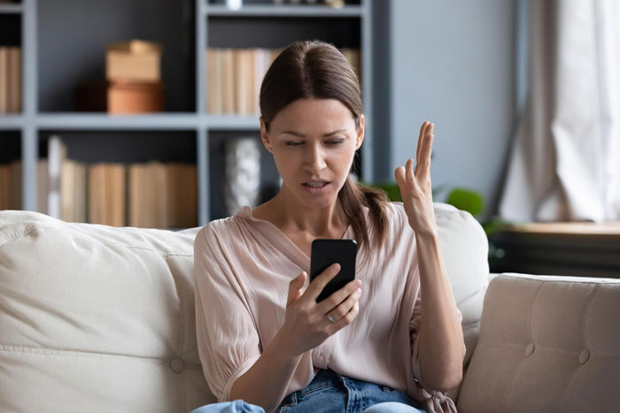 Woman trusted best friend with designer bag, got a fake one back; upset woman holding phone on a couch. Woman trusted best friend with designer bag, got a fake one back; upset woman holding phone on a couch.