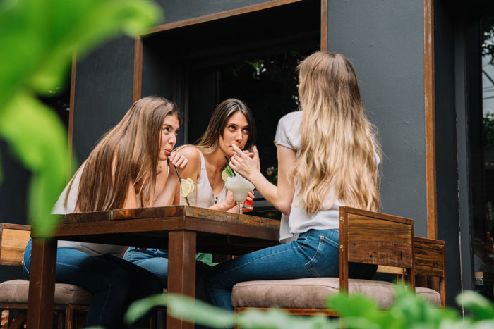 Three friends gather around a table, one holding a designer bag, illustrating the trust in a friendship. Three friends gather around a table, one holding a designer bag, illustrating the trust in a friendship.