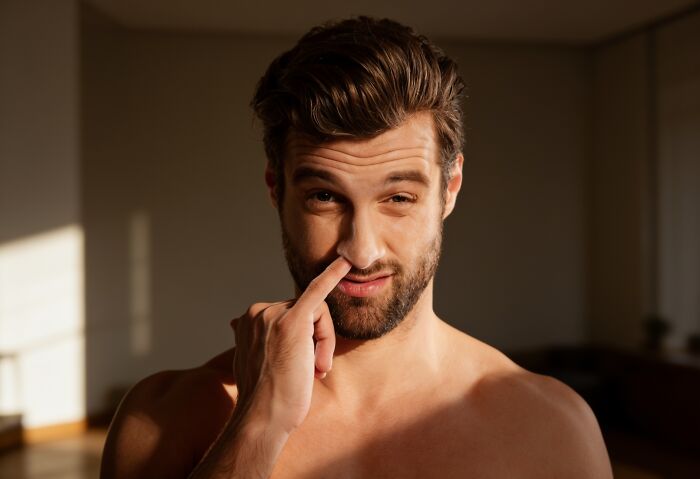 A man picking his nose, showing poor house etiquette among guests.