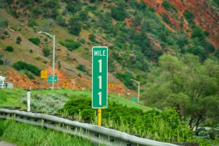 A green mile marker sign on an American road, highlighting American habits.
