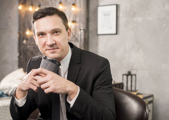 A guy in a suit, a job that makes women swipe left, holds a coffee cup in a professional setting.