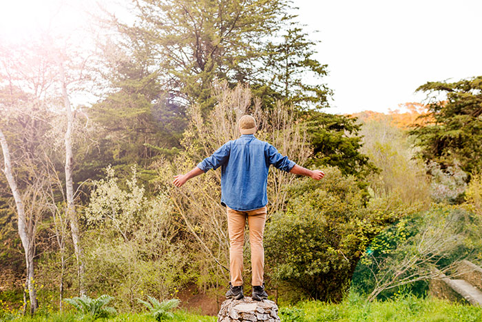 A man stands with arms outstretched in a forest, symbolizing a second chance at life after a brain tumor discovery.