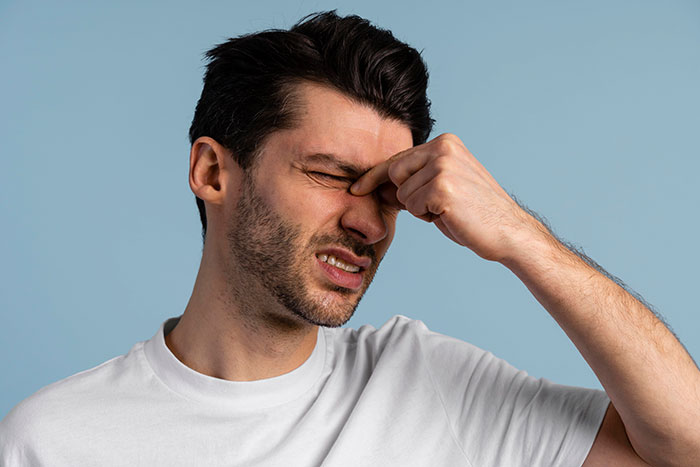 Distressed man rubbing his eyes, experiencing symptoms related to a giant brain tumor.