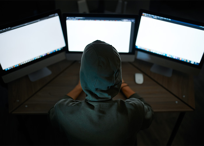 Hooded figure in front of multiple computer screens, representing the anonymous nature of doxxing and swatting pranks. Hooded figure in front of multiple computer screens, representing the anonymous nature of doxxing and swatting pranks.