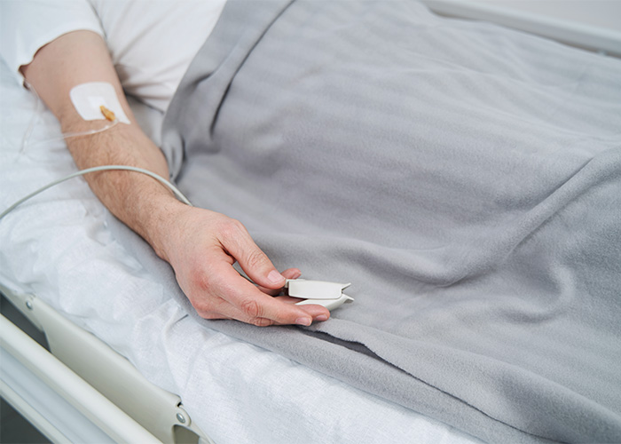 Man in a hospital bed with an IV and pulse oximeter, illustrating the tragic outcome of being paralyzed from a swatting prank. Man in a hospital bed with an IV and pulse oximeter, illustrating the tragic outcome of being paralyzed from a swatting prank.