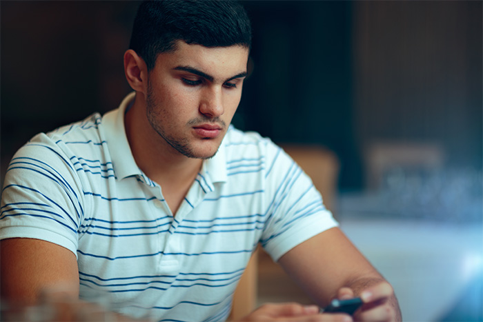 A pensive young man looking at his phone, representing the lonely man's emotional plea and the tough truth he exposes. A pensive young man looking at his phone, representing the lonely man's emotional plea and the tough truth he exposes.