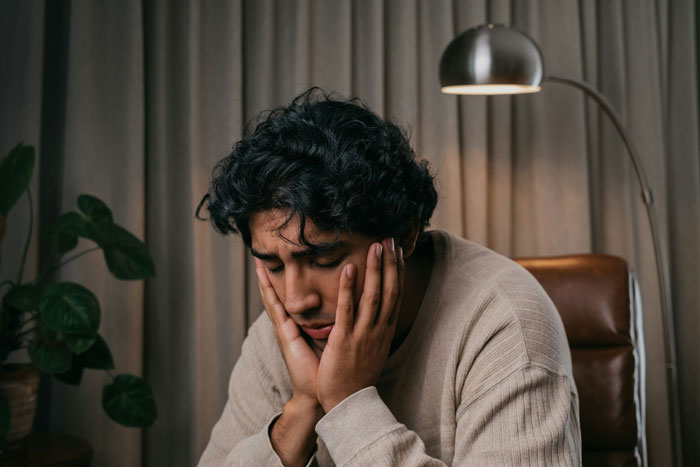 A man looking upset, resting his head on his hands, symbolizing the emotional toll of chasing the perfect body.