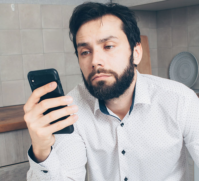 A man looking at his phone, realizing he lost more than he bargained for by proposing at his brother's wedding.
