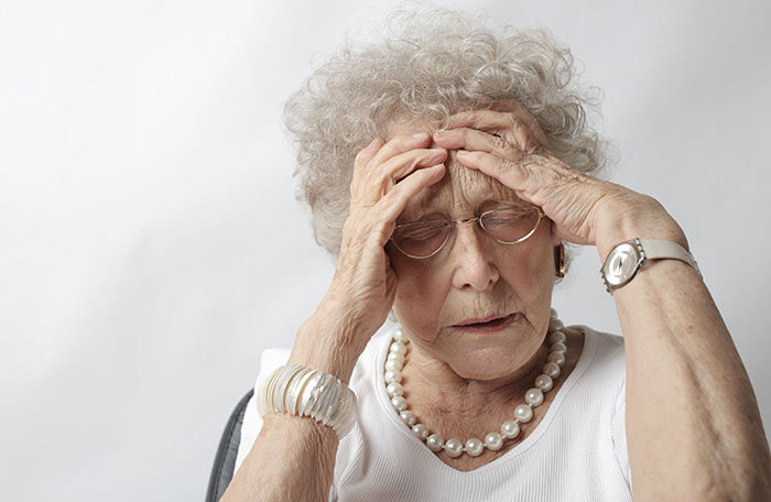 Entitled man plans to propose at brother's wedding, a stressed older woman clutching her head, experiencing distress.