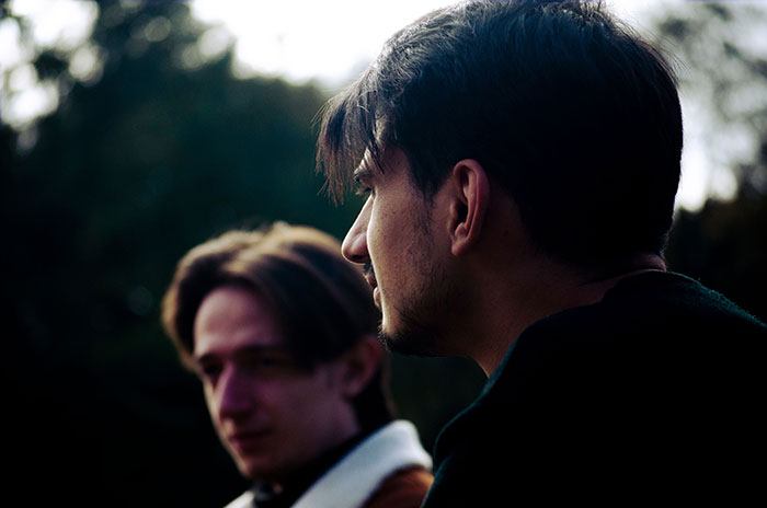 Two men looking away, one in focus. An entitled man plans to propose at his brother's wedding.
