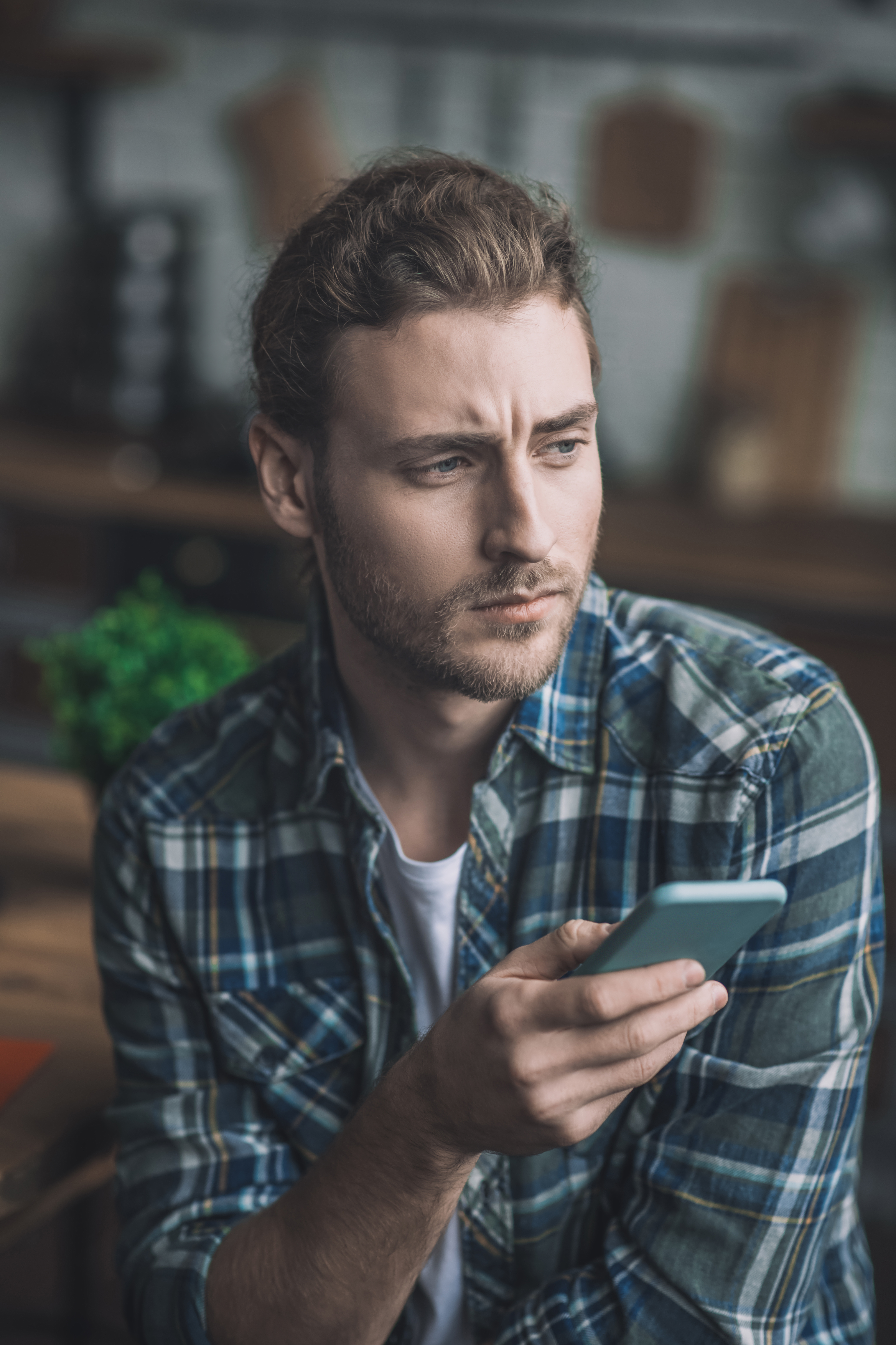 Concerned guy looks at his wife's phone, feeling weirded out by suspicious activity.